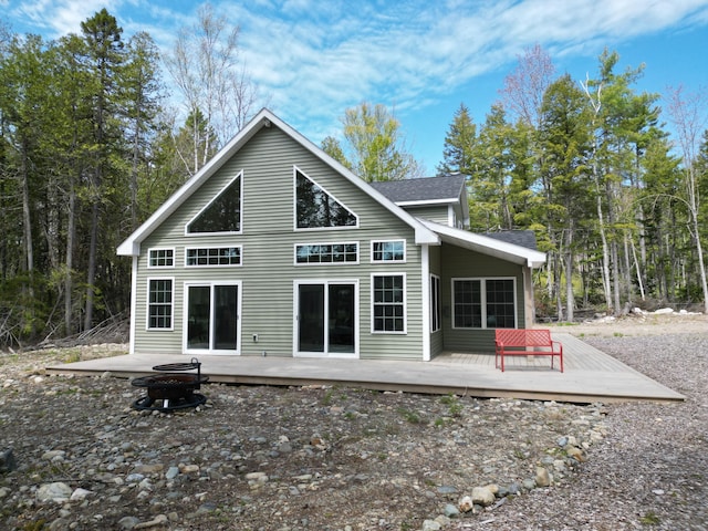 rear view of property with an outdoor fire pit, a deck, and roof with shingles