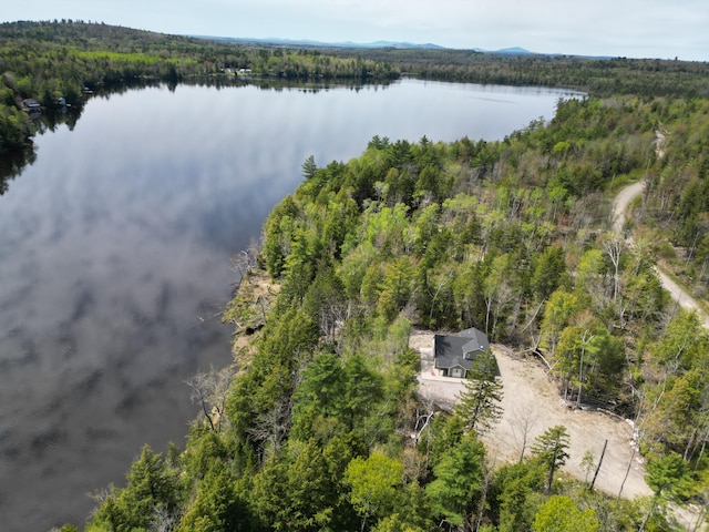 aerial view of property and surrounding area with a forest and a nearby body of water