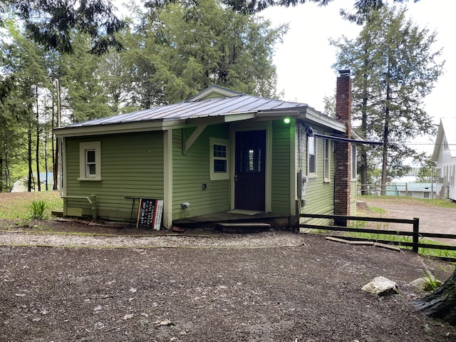 39 Salmon Rd, Madison, ME 04950 - view of front of house featuring fence, a chimney, metal roof, and a standing seam roof