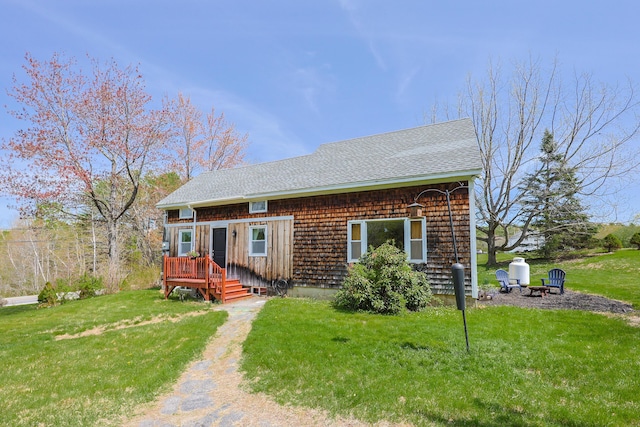 555 Meadow Rd, Topsham, ME 04086 - view of front of property with a deck, a front lawn, a shingled roof, and an outdoor fire pit