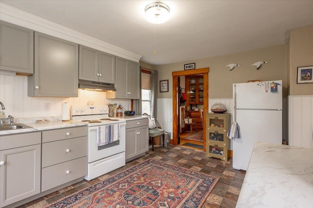 127 Harbor Rd, Friendship, ME 04547 - kitchen with white appliances, under cabinet range hood, a sink, gray cabinets, and a wainscoted wall