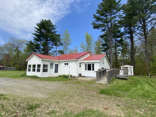 back of house with a shed, a chimney, a lawn, an outbuilding, and metal roof