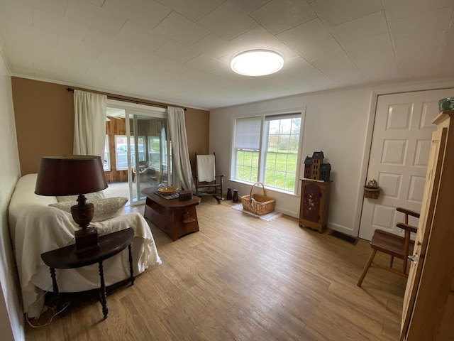 sitting room featuring light wood-style floors, ornamental molding, and baseboards