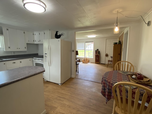 kitchen with white appliances, dark countertops, light wood-style flooring, white cabinetry, and crown molding