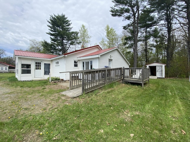 back of property with a wooden deck, a storage unit, an outbuilding, a yard, and metal roof