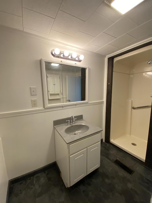 full bathroom featuring a shower stall, vanity, and wainscoting