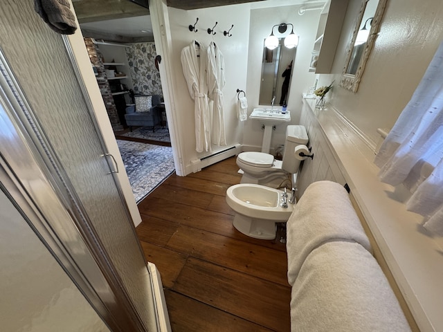 969 Washington St, Bath, ME 04530 - bathroom featuring hardwood / wood-style flooring, baseboard heating, toilet, a bidet, and a wood stove