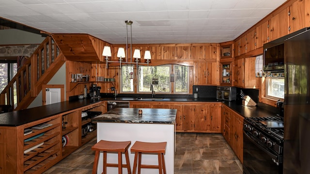 770 Poland Spring Rd, Casco, ME 04015 - kitchen with black appliances, dark countertops, a sink, brown cabinetry, and a kitchen island