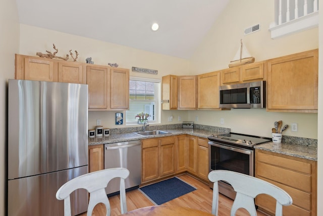 272 Mills Rd Unit 17, Kennebunkport, ME 04046 - kitchen with stainless steel appliances, light wood-type flooring, a sink, high vaulted ceiling, and light brown cabinetry