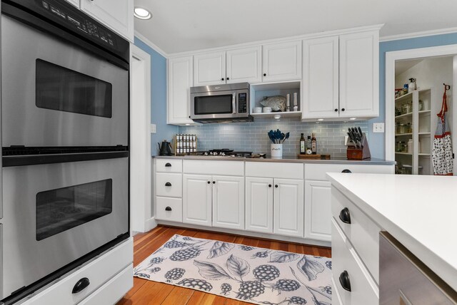 70 Summer St, Kennebunk, ME 04043 - kitchen featuring stainless steel appliances, light wood finished floors, white cabinetry, decorative backsplash, and crown molding