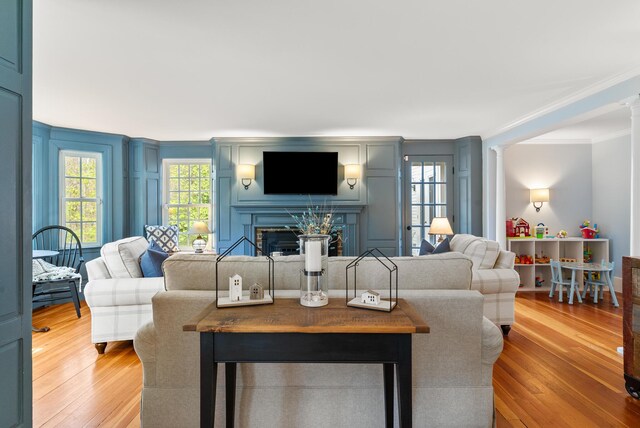 70 Summer St, Kennebunk, ME 04043 - living room with crown molding, light wood-style flooring, a fireplace, and decorative columns