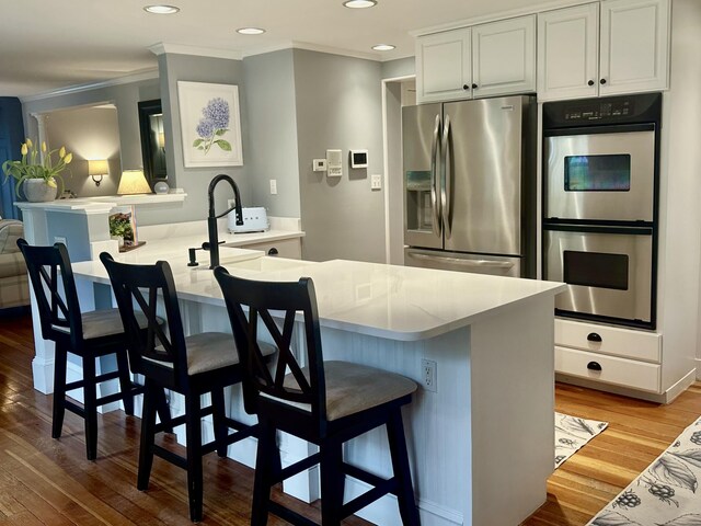 70 Summer St, Kennebunk, ME 04043 - kitchen with stainless steel appliances, crown molding, light wood-style flooring, a breakfast bar, and recessed lighting
