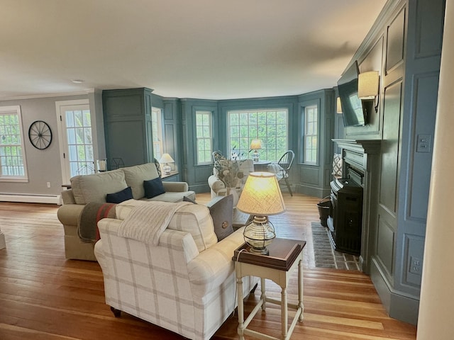 70 Summer St, Kennebunk, ME 04043 - living room featuring baseboard heating, light wood-style floors, crown molding, and healthy amount of natural light