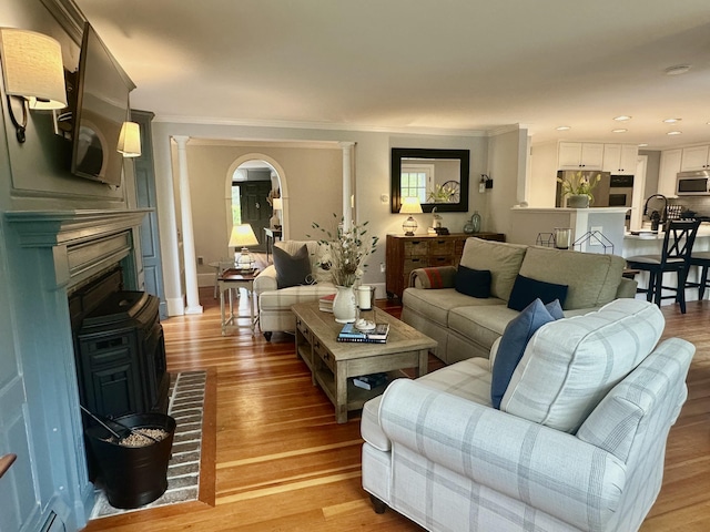 70 Summer St, Kennebunk, ME 04043 - living room featuring light wood finished floors, crown molding, a fireplace, recessed lighting, and arched walkways