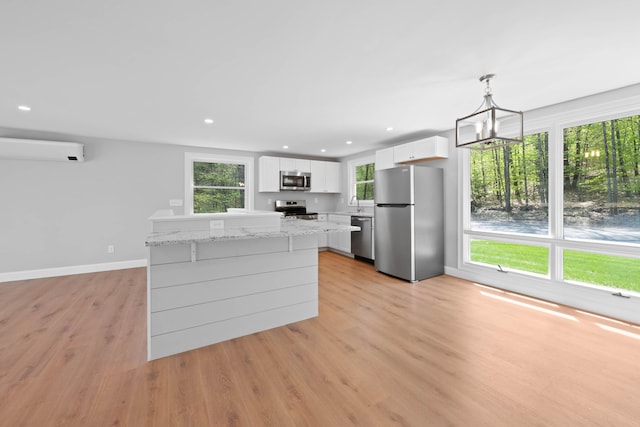 347 Brownfield Rd, Porter, ME 04068 - kitchen featuring appliances with stainless steel finishes, a wall mounted air conditioner, light wood-style flooring, white cabinetry, and a chandelier
