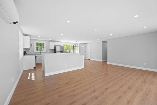 347 Brownfield Rd, Porter, ME 04068 - unfurnished living room featuring a wall unit AC, recessed lighting, light wood-style floors, a chandelier, and baseboards