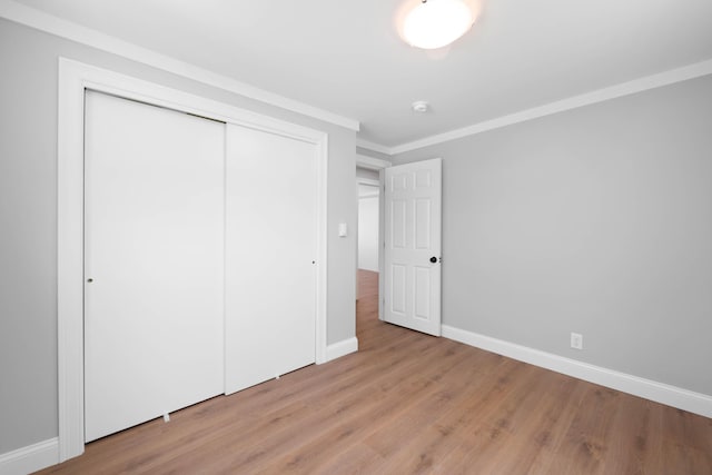 347 Brownfield Rd, Porter, ME 04068 - unfurnished bedroom featuring a closet, baseboards, light wood finished floors, and crown molding