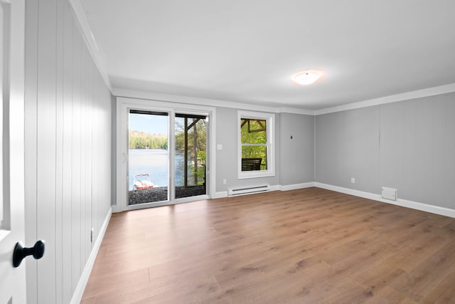 347 Brownfield Rd, Porter, ME 04068 - empty room featuring a baseboard heating unit, wood finished floors, crown molding, baseboards, and a water view