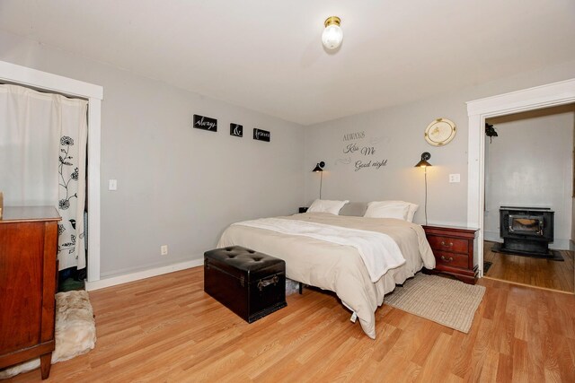 22 Pleasant St, Phillips, ME 04966 - bedroom with a wood stove, light wood-type flooring, and baseboards