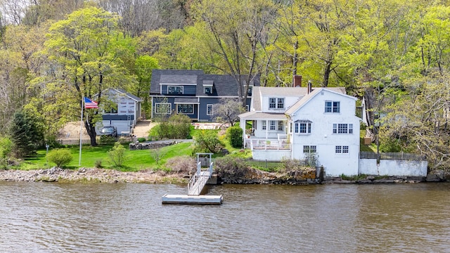 rear view of property with a water view, a wooded view, and a chimney