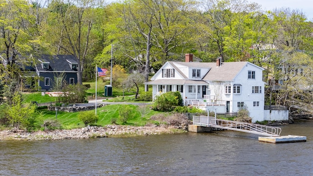 back of house with a chimney and a water view