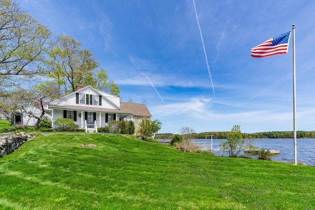 bungalow with a porch, a water view, a front lawn, and a chimney