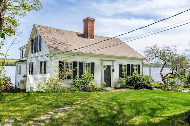 back of property featuring a chimney, roof with shingles, and a lawn