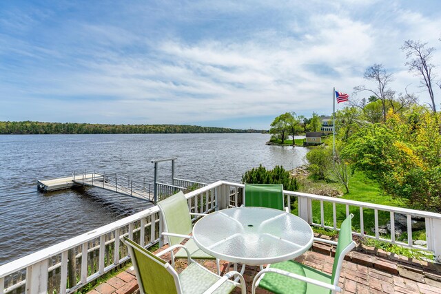 balcony featuring a water view, a floating dock, and outdoor dining space