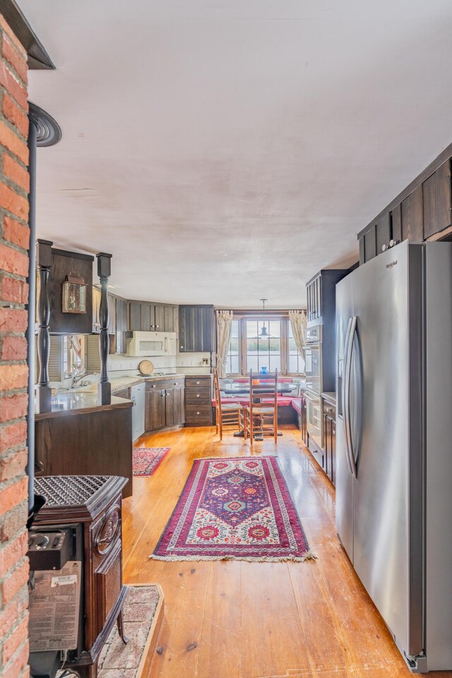 kitchen featuring stainless steel appliances, a wood stove, light wood-style floors, and light countertops