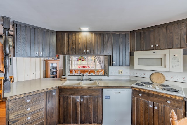 kitchen with white appliances, a sink, dark brown cabinetry, and a peninsula