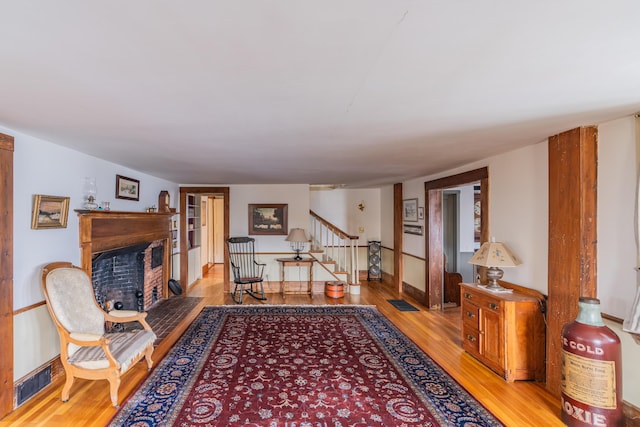 living area featuring light wood-style flooring, stairway, a fireplace, and baseboards