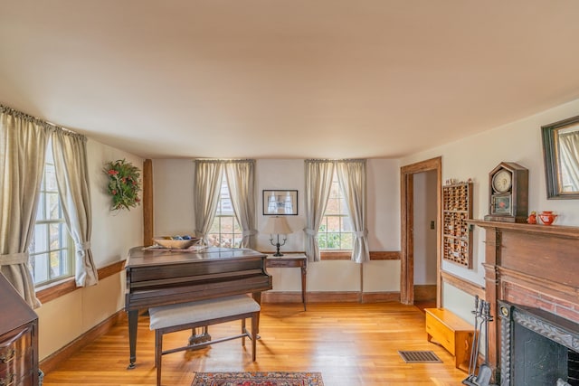 sitting room with a fireplace with flush hearth, light wood-style flooring, and baseboards