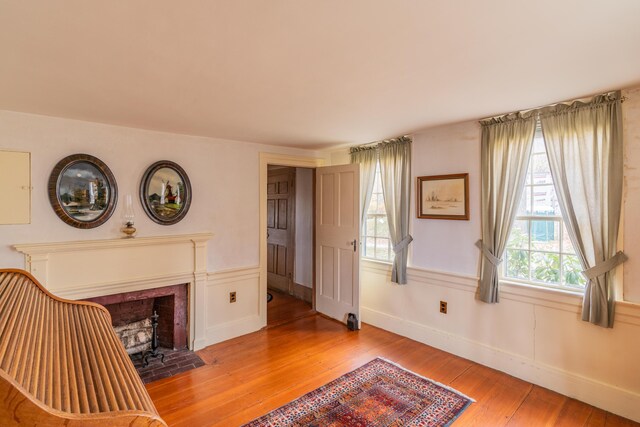 sitting room featuring light wood-style floors, healthy amount of natural light, a fireplace with flush hearth, and baseboards