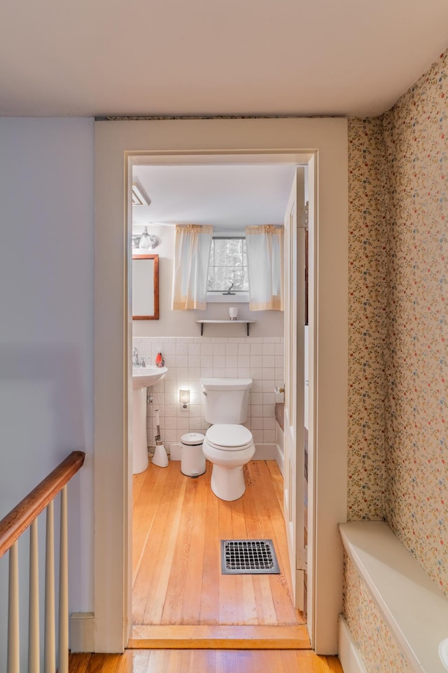 full bath featuring toilet, hardwood / wood-style floors, and tile walls