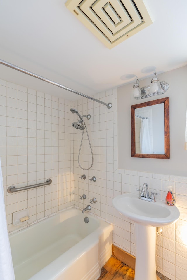 full bathroom with shower / tub combo with curtain, tile walls, wood finished floors, and a sink