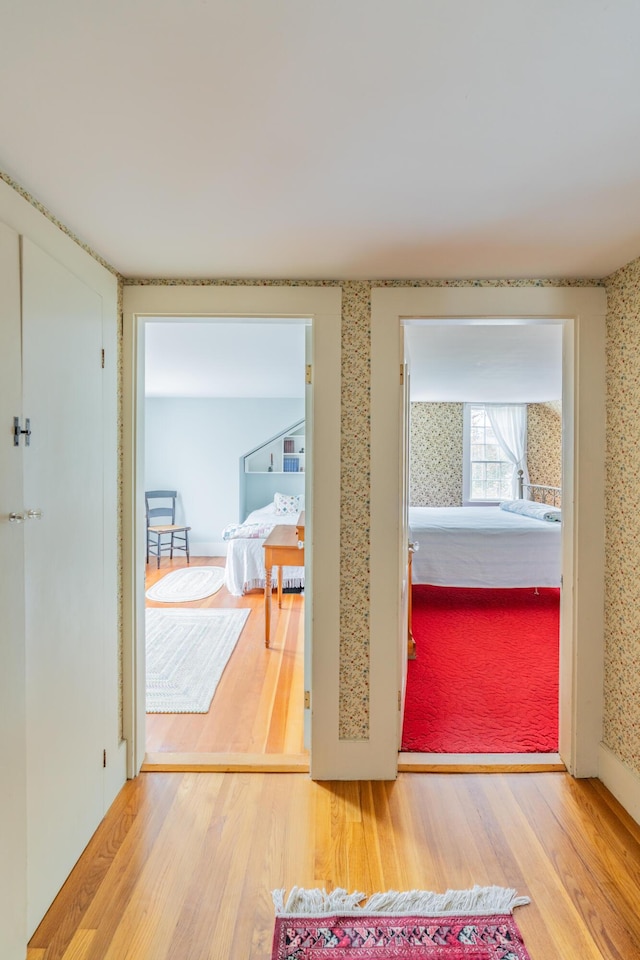 corridor featuring wood finished floors and wallpapered walls
