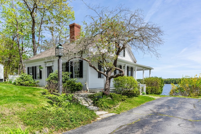view of property exterior featuring a lawn, a chimney, and covered porch