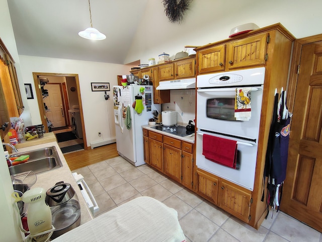 kitchen featuring white appliances, a sink, light countertops, under cabinet range hood, and lofted ceiling