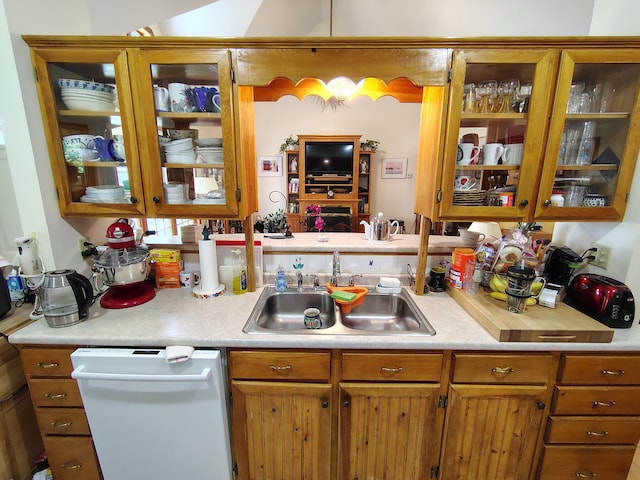 kitchen with dishwasher, a sink, light countertops, and brown cabinetry