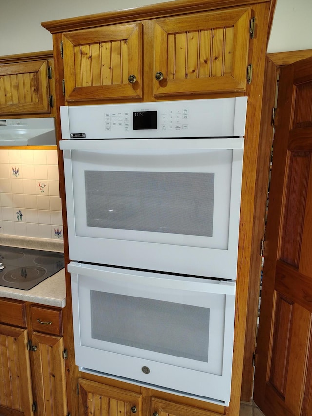 100 Weber Ln, Calais, ME 04619 - kitchen view of double oven, brown cabinetry, black electric cooktop, and ventilation hood