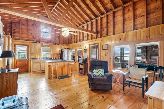 567 Phinney Farm Rd, Lincoln, ME 04457 - living area with high vaulted ceiling, light wood-style floors, wood ceiling with exposed beams, a ceiling fan, and wood walls