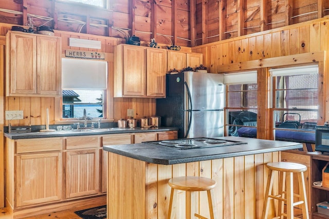 567 Phinney Farm Rd, Lincoln, ME 04457 - kitchen featuring freestanding refrigerator, a sink, dark countertops, a kitchen breakfast bar, and wood walls