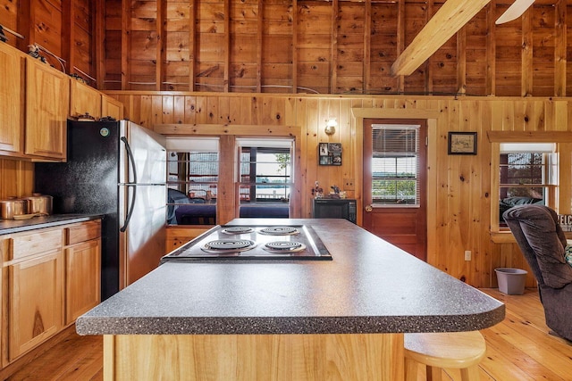 567 Phinney Farm Rd, Lincoln, ME 04457 - kitchen featuring light wood finished floors, a center island, wood walls, freestanding refrigerator, and dark countertops