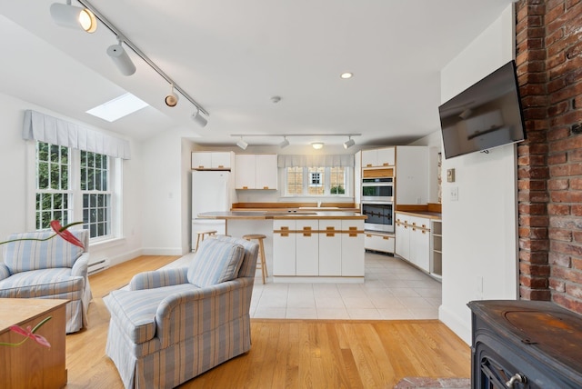 7 Clubhouse Dr, Kennebunk, ME 04043 - kitchen with track lighting, stainless steel double oven, open floor plan, a skylight, and freestanding refrigerator
