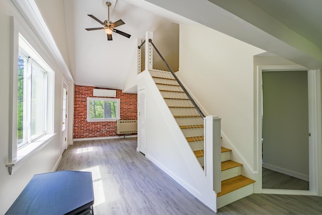 204 Weymouth Rd, Morrill, ME 04952 - staircase with brick wall, wood finished floors, ceiling fan, baseboards, and high vaulted ceiling