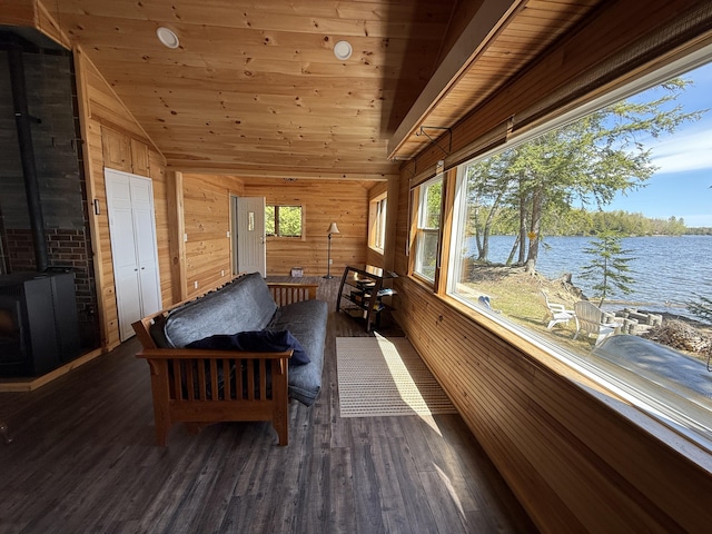 sunroom / solarium with a wood stove, lofted ceiling, and a water view