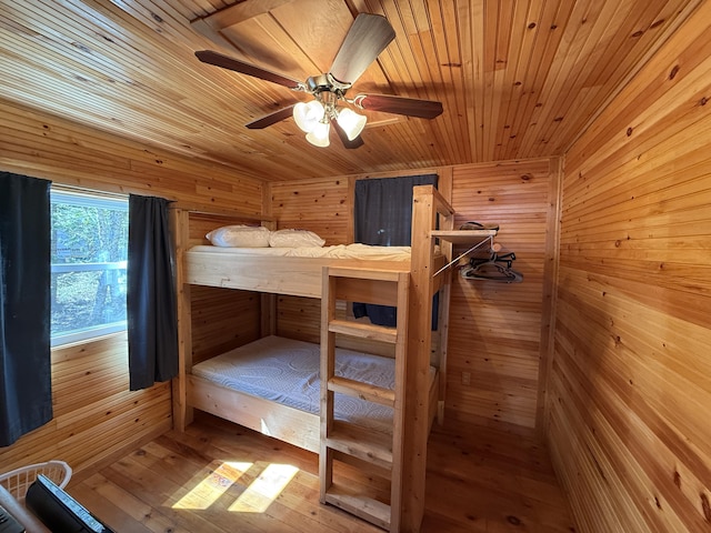 bedroom featuring wood walls, wooden ceiling, ceiling fan, and hardwood / wood-style floors