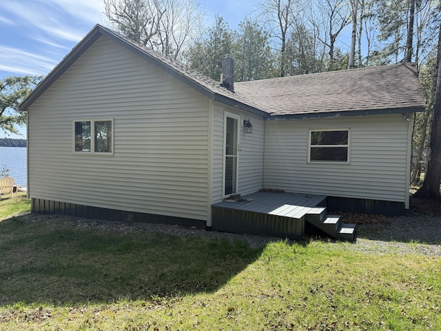 rear view of house featuring a lawn, roof with shingles, and a wooden deck