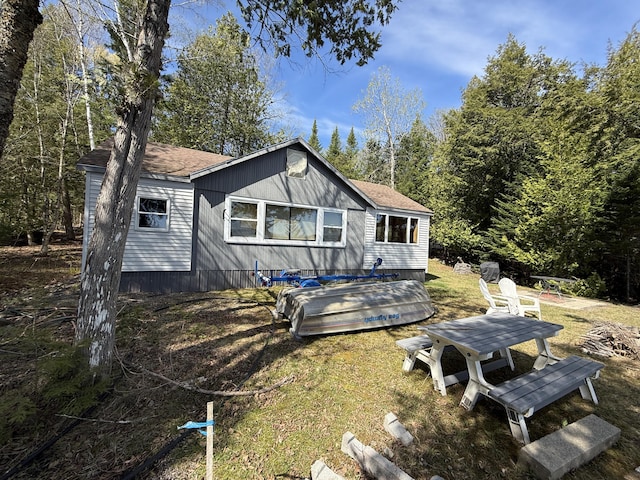 rear view of property featuring roof with shingles and a lawn