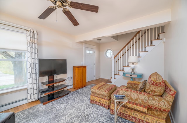 626 Wiscasset Rd, Pittston, ME 04345 - living area featuring a baseboard heating unit, wood finished floors, ceiling fan, stairs, and baseboards